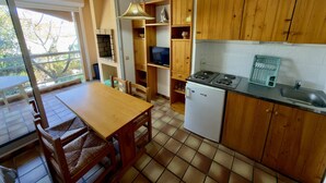 Cuina amb armaris de fusta, una cuina, un rentamops i una zona de menjador amb caires.