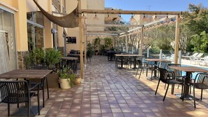 Un pati exterior amb taules i cadires, una pérgola i una cadira hamaca penjada.
