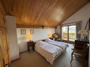 A bedroom with a wooden ceiling, two beds, a desk, a chair, and a window with a view. - Spacious apartment with parking - 6 guests (Méribel)