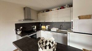 A modern kitchen with white cabinets, a black countertop, and a microwave. - Spacious apartment with parking - 6 guests (Méribel)