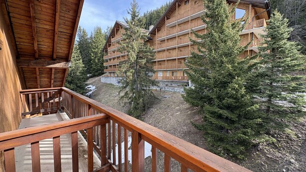A wooden building with multiple balconies, surrounded by trees. - Spacious apartment with parking - 6 guests (Méribel)