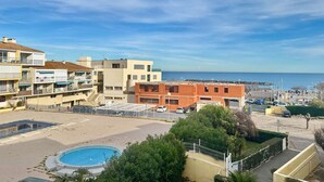 Um hotel à beira-mar com piscina, vários edifícios e vista para o mar.