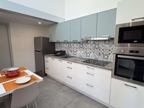 A modern kitchen with white cabinets, a built-in oven, a microwave, and a patterned backsplash. - Neat air-conditioned pavilion by the sea - 4 guests (Gruissan)