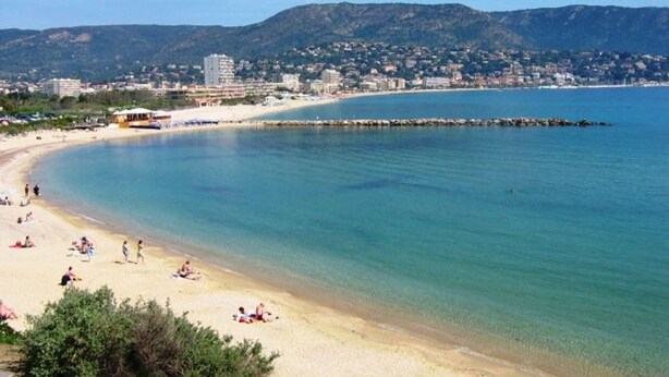 Una spiaggia con acque limpide, una costa sabbiosa e uno skyline sullo sfondo.
