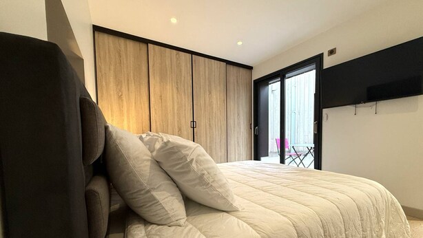 Un dormitorio con cama, armario y televisor montado en la pared.