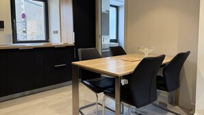 Una cocina moderna con zona de comedor, que incluye una mesa de madera, sillas negras y un ventanal con vistas a la calle.