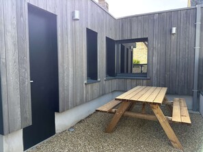A wooden deck with a picnic table, a door, and windows. - Renovated house near beach - 4 guests (Perros-Guirec)
