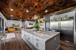 A modern kitchen with a large island, stainless steel appliances, and a wooden ceiling. - Now Open! Be the first to stay in The Grand View! (Sevierville)