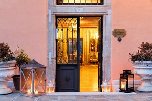 A hotel entrance with a black door, a sign reading 'Ca'Alberti', and two potted plants on either side.