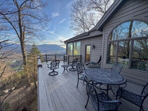 Eine Terrasse mit Gartenmöbeln, großen Fenstern und Blick auf die Berge.
