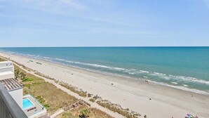 A beach with a clear sky, a swimming pool, and a building with a flat roof. - Oceanfront 1BR + Beach Access + Dog Friendly (Myrtle Beach)