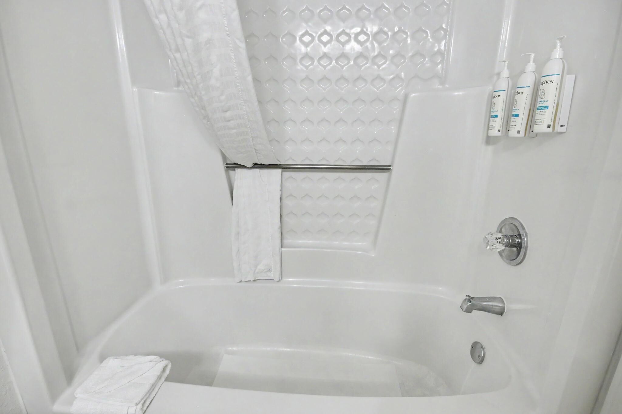 A bathroom with a bathtub, a towel rack, and toiletries.