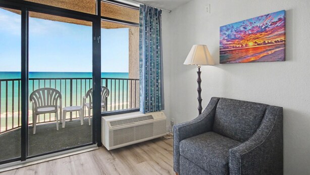 A balcony with a view of the ocean, a chair, a table, a heater, and a painting on the wall. - Oceanfront King Room + Beach Access + Dog Friendly (Myrtle Beach)