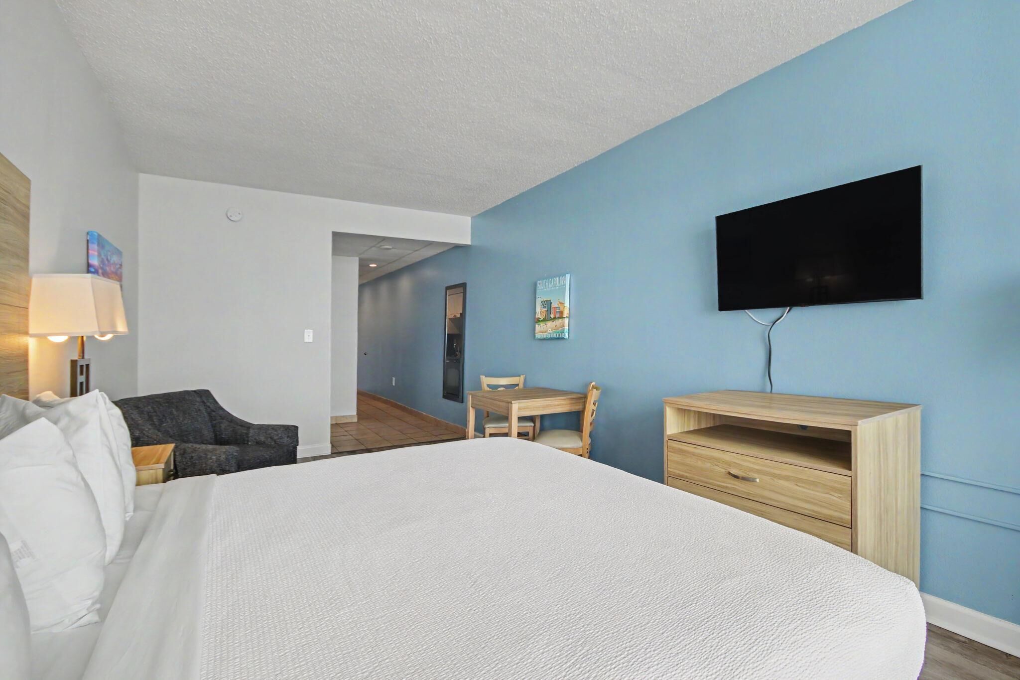 Hotellihuone, jossa on sänky, työpöytä, tuoli, televisio ja lamppu.