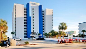 A multi-story hotel with a prominent 'OceanPark' sign, a parking lot, and palm trees. - Oceanfront King Room + Beach Access + Dog Friendly (Myrtle Beach)