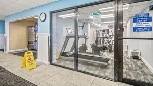A fitness center with exercise equipment, a clock, and a sign indicating availability times. - Oceanfront King Room + Beach Access + Dog Friendly (Myrtle Beach)