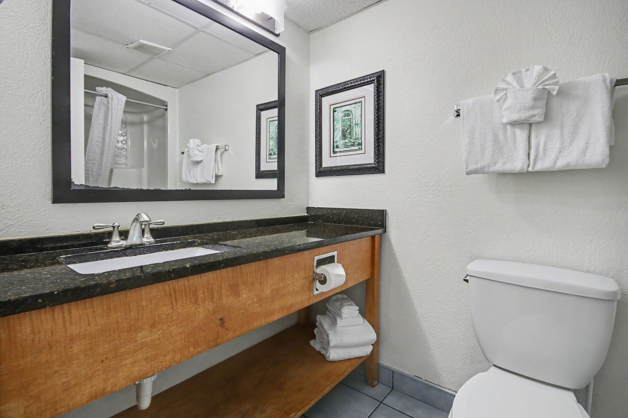 Een badkamer met een wastafel, spiegel, toilet en handdoekhouder.