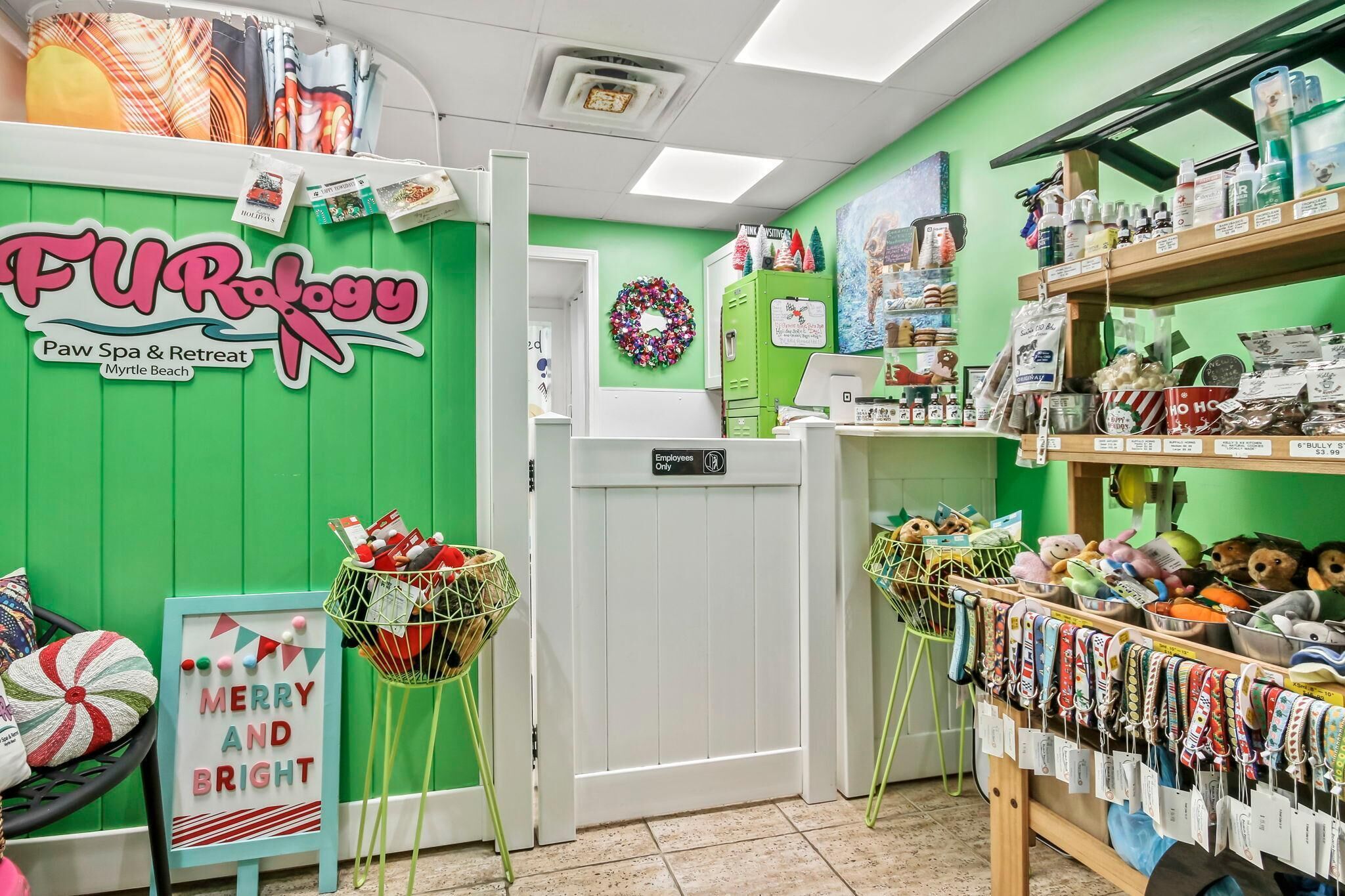 A paw spa and retreat with a green wall, a 'Merry and Bright' sign, and shelves with various items.