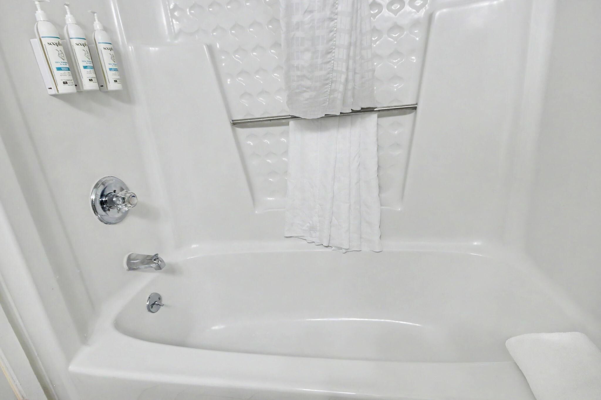 Une salle de bain avec une baignoire, un rideau de douche et des articles de toilette fixés au mur.