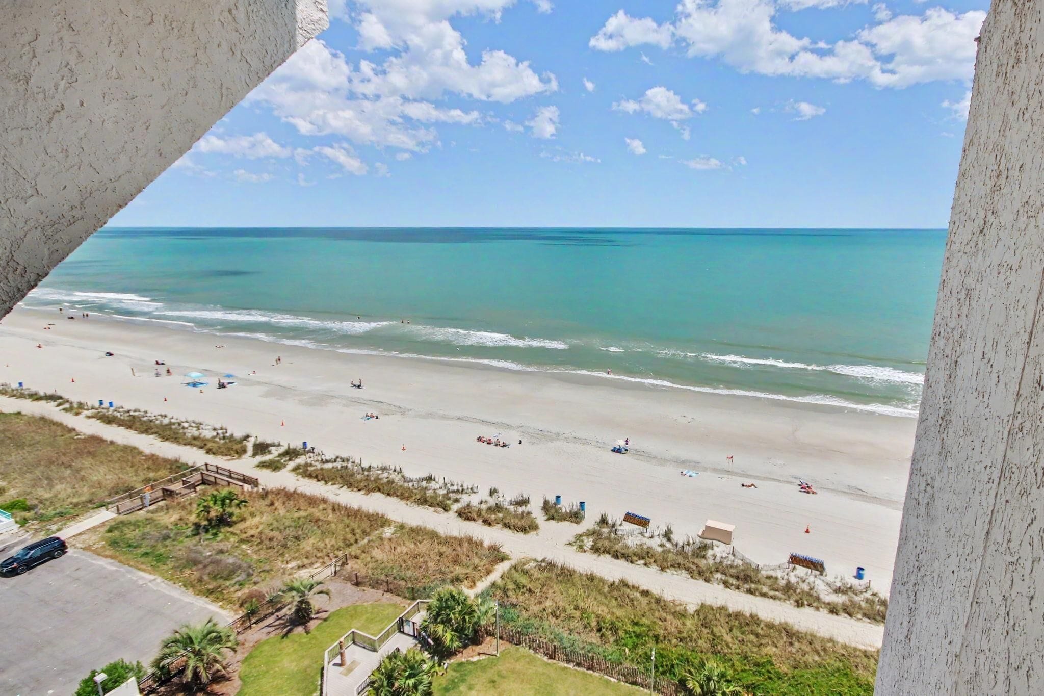 A beach with a clear view of the ocean, a sandy shoreline, and a few people.