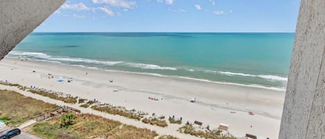 Una playa con vista despejada al océano, una orilla arenosa y algunas personas.