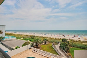 A beach view from a balcony with a pool and lounge chairs. - Oceanfront Two Queen Room + Beach + Dog Friendly (Myrtle Beach)