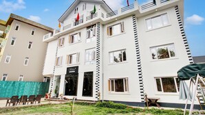 A multi-story hotel with a balcony, a sign reading 'Collection,' and a flag on top. - Deluxe Rest A While (Srinagar)
