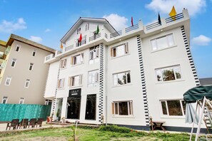 Un hotel de varios pisos con un balcón, un letrero que dice 'Collection' y una bandera en la cima.