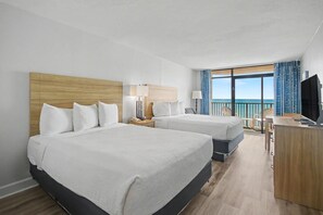 Een hotelkamer met twee bedden, een bureau, een televisie en een balkon met uitzicht.