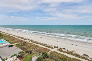 Ein Strand mit Schwimmbad, Parkplatz und Blick auf den Ozean.