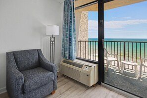 Ein Balkon mit Blick auf das Meer, ein grauer Sessel, eine Stehlampe und ein Heizgerät.