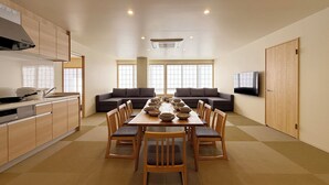 A modern kitchen with a dining table set for six, a sofa, and a TV on the wall. - WAKO Ekimae (Hiroshima City)