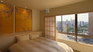 A hotel room with a bed, a view of the city through large windows, and traditional decor. - WAKO Ekimae (Hiroshima City)
