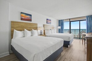 Ein Hotelzimmer mit zwei Betten, einem Schreibtisch, Stühlen und einem Balkon mit Blick.