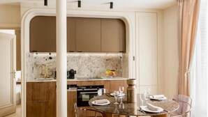 Eine moderne Küche mit Holzschränken, einer Marmorarbeitsplatte und einem Essbereich mit rundem Tisch und Stühlen.