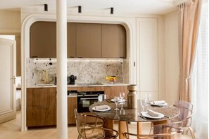 Eine moderne Küche mit Holzschränken, einer Marmorarbeitsplatte und einem Essbereich mit rundem Tisch und Stühlen.