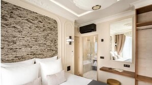 Ein Hotelzimmer mit einem großen Bett, einer Wand mit Steinoptik, einem Spiegel und einem Holzregal.