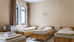A hotel room with four beds, a coffee machine, a TV, and a window with curtains. - Olchazor hotel (Tashkent)