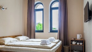 A room with two beds, a wooden nightstand with a kettle, cups, and a basket. - Olchazor hotel (Tashkent)