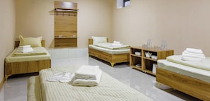 A hotel room with two beds, a wooden wardrobe, a small shelf with toiletries, and a tiled floor. - Olchazor hotel (Tashkent)