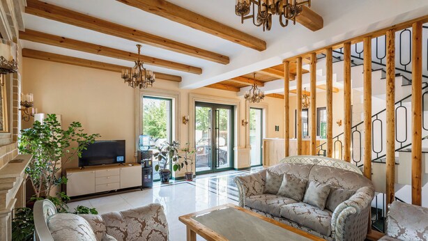 A spacious living area with a wooden ceiling, a sofa set, a television, and a staircase. - Olchazor hotel (Tashkent)