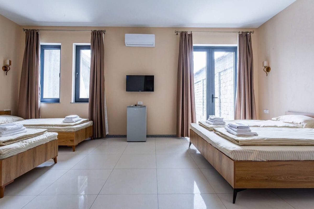 Een hotelkamer met twee bedden, een televisie en een airconditioning.