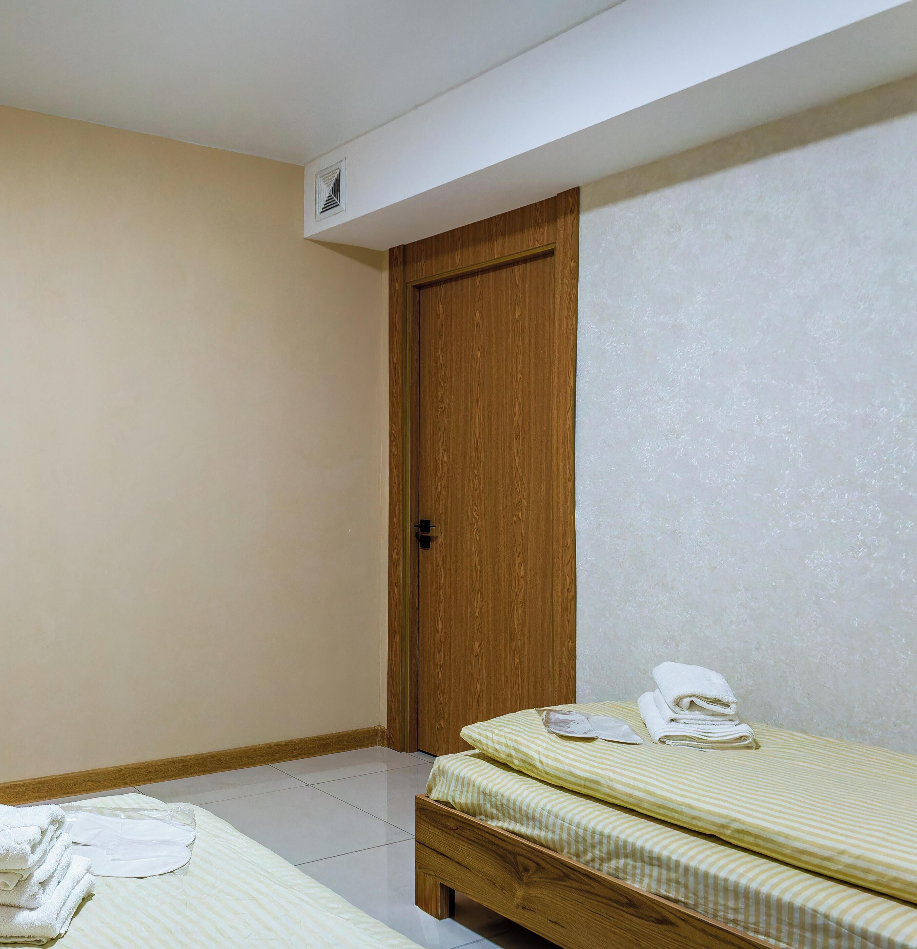 Un dormitorio con puerta de madera, una cama con ropa de cama a rayas y suelo de baldosas.