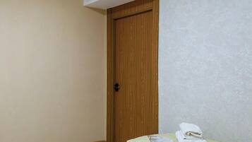 Un dormitorio con puerta de madera, una cama con ropa de cama a rayas y suelo de baldosas.
