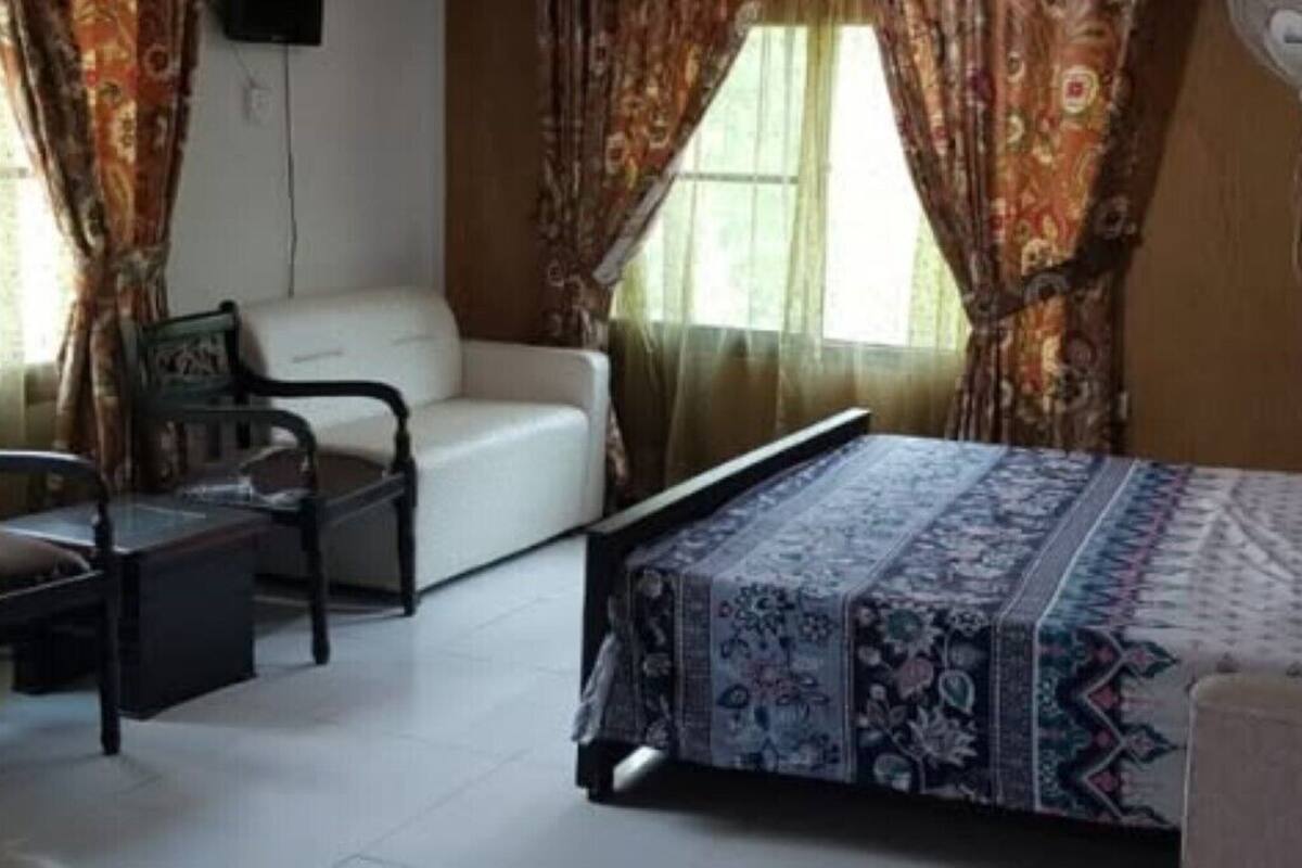 A room with a bed, a chair, a desk, and a window with curtains.
