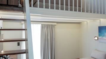 Un dormitorio estilo loft con una escalera, un sofá, una mesa redonda de centro y un cuadro en la pared.