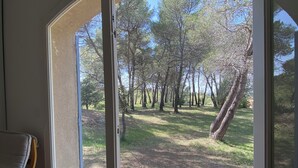 A room with a sliding glass door leading to an outdoor area with trees and a grassy path. - La Grande Bastide (Grambois)
