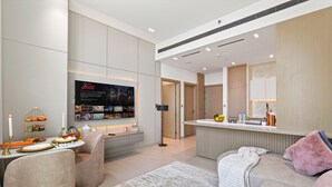 Ein modernes Wohnzimmer mit Flachbildfernseher, einem Essbereich mit Tisch und einer gemütlichen Sitzecke mit Sofa und Sessel.