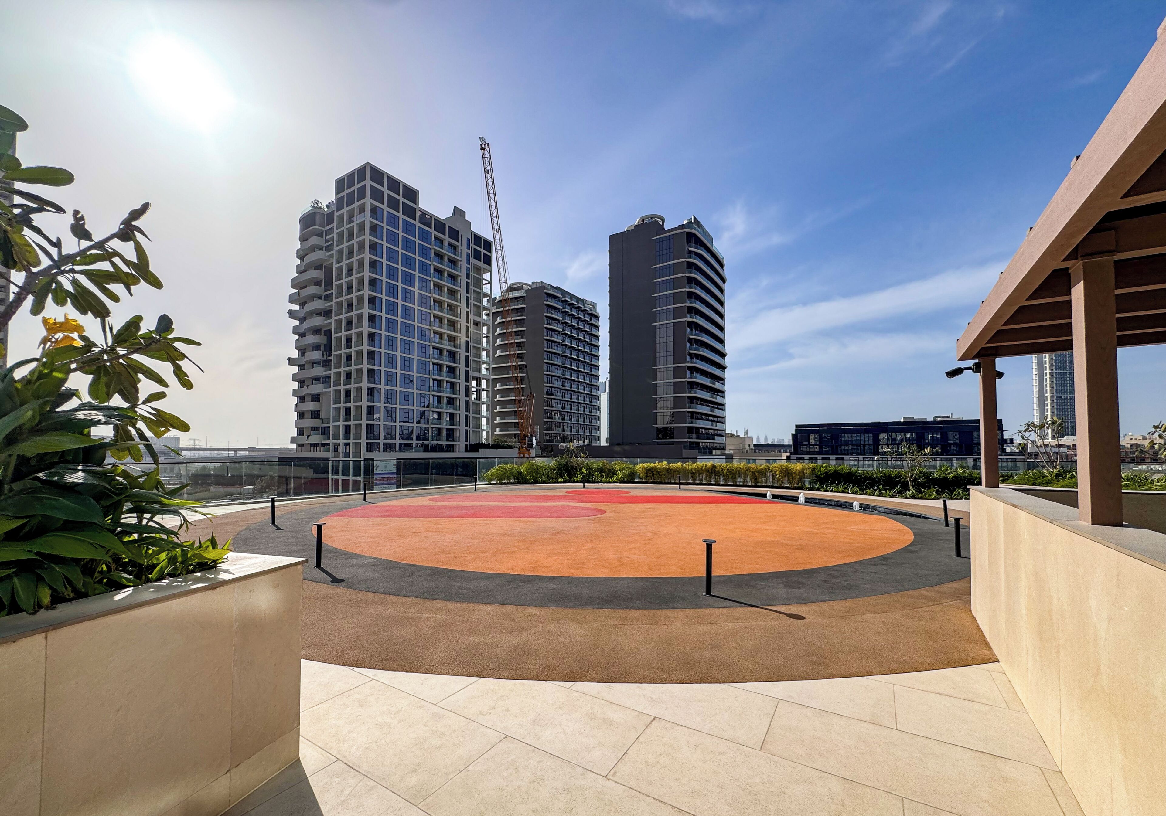 Una terraza en la azotea con un área de juegos circular, rodeada de edificios modernos y un cielo despejado.