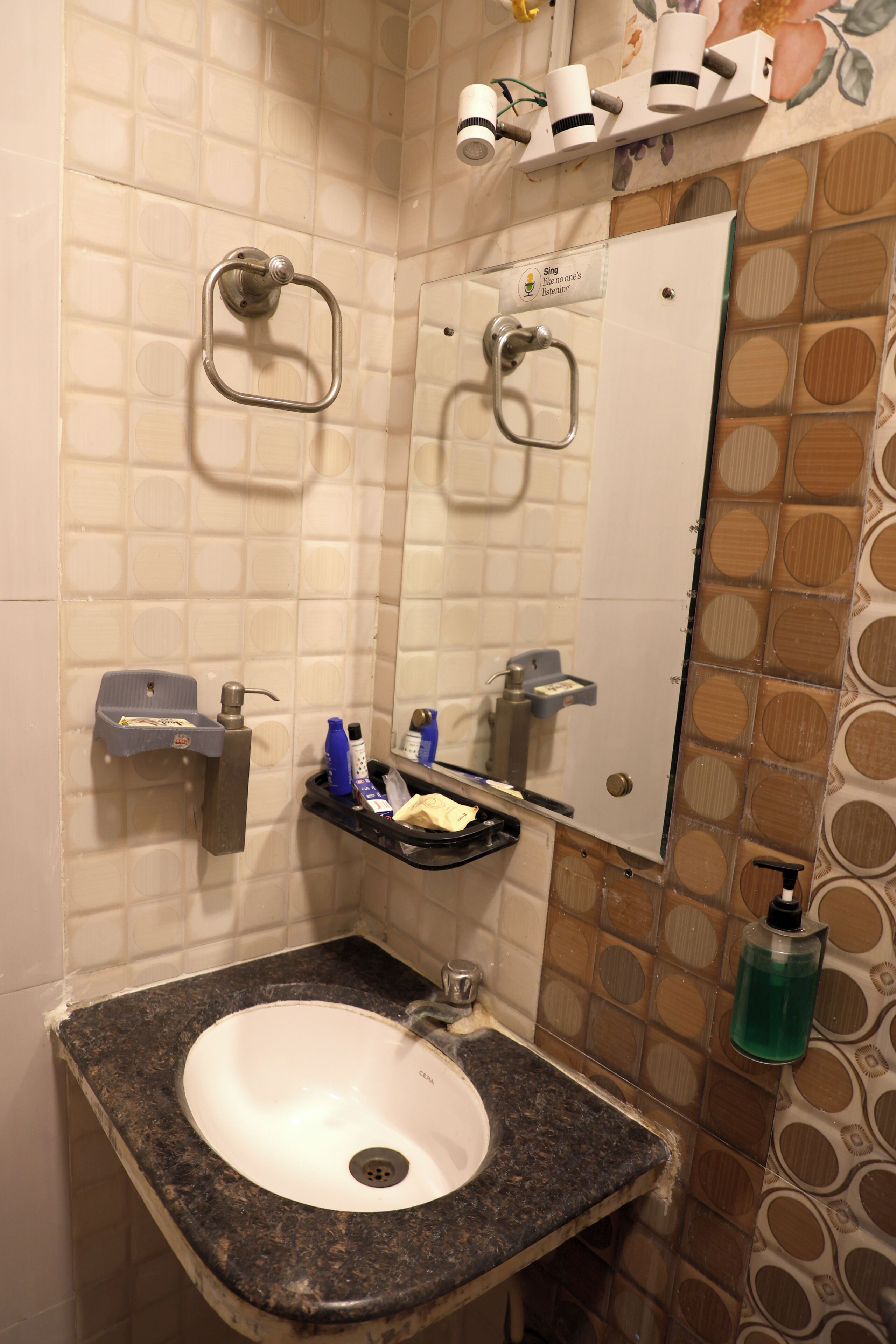 A bathroom with a sink, mirror, towel rack, and a shelf with toiletries.
